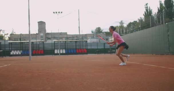 Attraktiv idrottsman innehar nära Net I Tennisbana. Ung atletisk kvinna spelar tennis, promenader i en inomhus domstol, kvinnlig spelare blir på en spelplats, träningsdag — Stockvideo