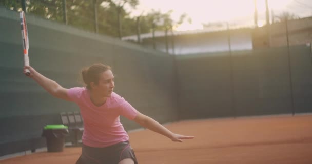 Młoda kobieta przechodząca przez kort tenisowy z rakietą. Widok z tyłu atrakcyjnej brunetki w niebieskiej koszuli i czarnych spodenkach wchodzących w kort tenisowy. Pełna długość następnie strzał z miejsca kopiowania — Wideo stockowe