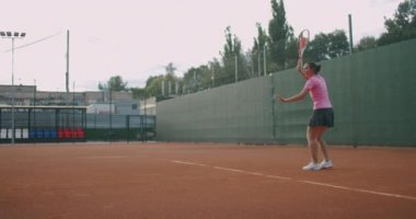 Kadın tenisçi profesyonel stadyumda maç sırasında iş başında. O markasız spor giysiler giyiyor. Stadyum