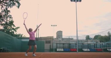 Tenis maçına hazırlanan genç bir bayan tenisçinin düşük açılı görüntüsü. Bir kadın atlet spor antrenmanı sırasında topa güçlü bir şekilde vuruyor. Ticari kullanım görüntüleri