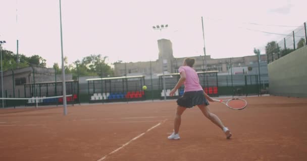 Sahada tenis oynayan beyaz bir kadın ağır çekimde topu geri getiriyor. — Stok video