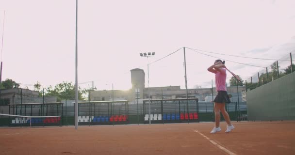 Tênis profissional, determinada menina jogador esporte batendo raquete na bola na quadra vermelha profissional durante o jogo ao ar livre, câmera lenta — Vídeo de Stock