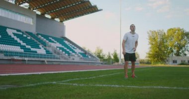Tribünlerin yakınındaki bir futbol sahasında vites değiştiren bir futbolcu pas alır ve ağır çekimde bir futbol topuyla kaçar.