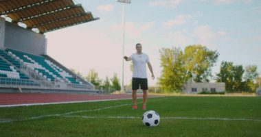 Ağır çekim: Futbolcu topa vuruyor. Futbolcudan düşük açılı tekme. Futbol maçında futbola başlamak üzere olan profesyonel futbolcu.