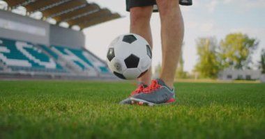 Futbol sahasında ağır çekimde spor aletleriyle zıplayan bir adam futbol topunu sektirir.