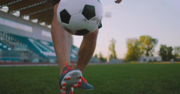 Przechyl się w zwolnionym tempie samca z profesjonalnej ligi piłki nożnej żonglerka piłkę na nodze w polu gry na świeżym powietrzu w słoneczny letni dzień — Wideo stockowe