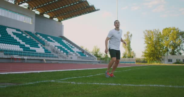 Футболист в снаряжении на футбольном поле получает пропуск и технически обрабатывает входящий футбольный мяч — стоковое видео