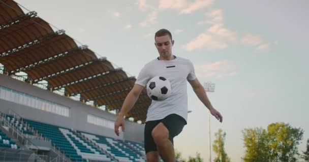 Profi focista zsonglőrködik egy labdával. Socker egy játékos fehér labdarúgó egyenruhában a stadionban — Stock videók