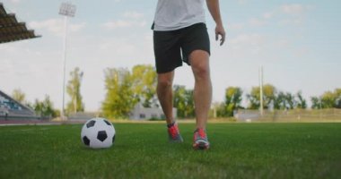 Stadyumdaki futbol sahasında futbol topuyla koşan bir erkek futbolcunun yakın çekimi mükemmel top sürüşü ve top kontrolünü gösteriyor..
