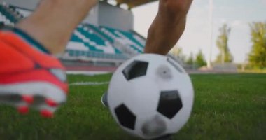 Stadyumdaki futbol sahasında futbol topuyla koşan bir erkek futbolcunun fevkalade top sürüşünü gösteriyor.