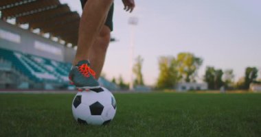 Profesyonel futbol ligindeki ağır çekimde, güneşli bir yaz gününde sahada top bacağında hokkabazlık yapan erkek.
