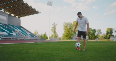 Futbol sahasında ağır çekimde spor aletleriyle zıplayan bir adam futbol topunu sektirir.