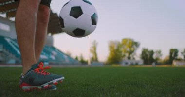 Profesyonel futbol ligindeki ağır çekimde, güneşli bir yaz gününde sahada top bacağında hokkabazlık yapan erkek.