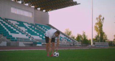 Çorap topunu çimenliğe koy ve yeşil çimenli stadyumda topa vur. Profesyonel bir futbolcu ağır çekimde topa vurur.