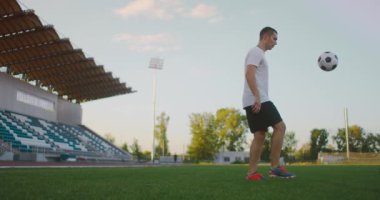 Profesyonel futbolcu topla hokkabazlık yapıyor. Stadyumda beyaz futbol forması giyen bir oyuncuyu socker