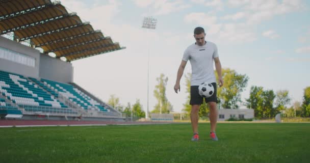 Profesjonalny mężczyzna piłkarz sportowiec na boisku piłkarskim w zwolnionym tempie w sprzęt sportowy odbić piłkę nożną — Wideo stockowe