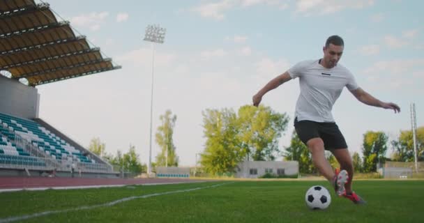 Fotbalista na stadionu demonstruje kapání s fotbalovým míčem, zatímco vede meč při běhu. Vynikající dovednosti fotbalisty a ovládání míče