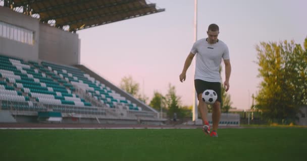 Döntse fel a lassított felvétel a férfi a profi futball liga zsonglőrködés labdát a lábát a szabadban játszótér napsütéses nyári napon — Stock videók