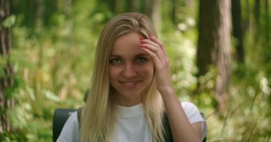 Atmosferik yakın plan, genç, güzel, gülümseyen kız şapkalı, saçları havada, ormanda ağır çekimde.