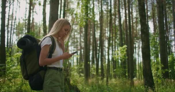 Femme attrayante se détendre en forêt et en utilisant smartphone à l'extérieur. Femme randonnée dans la forêt et dactylographie message sur Smartphone. Randonneuse solo utilisant un téléphone intelligent. — Video