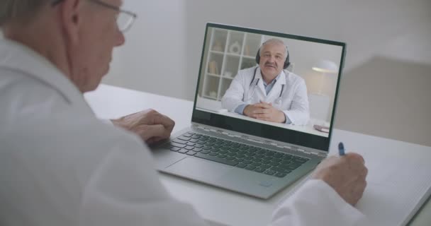 Praktický lékař poslouchá on-line přednášku profesora medicíny, prohlížení obrazovky notebooku a psaní poznámek — Stock video