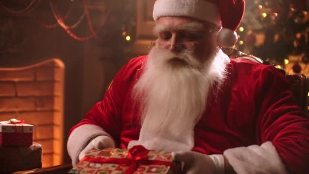 Santa Claus vtáhne dárek do kamery. Vánoční čas skutečný Santa Claus s vousy dává dárek v krabici.