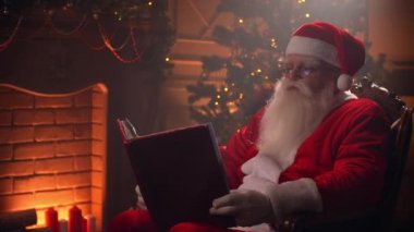 Noel Baba kostümü giymiş sakallı son sınıf öğrencisi temalı odada kırmızı kapaklı sayfaları karıştırıyor. Noel ruhu kavramı kapanıyor..