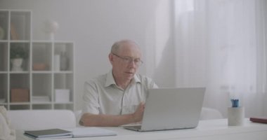 Yaşlı avukat müşteriyle internet üzerinden iletişim kuruyor, web kamerasıyla danışmanlık yapıyor, ofiste oturuyor.