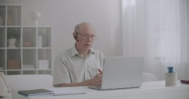 İnternetten e-öğrenme, yaşlı adam ders veriyor, evde dizüstü bilgisayarın önünde oturuyor, internetten iletişim kuruyor.