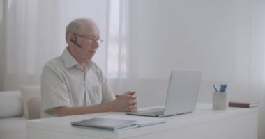 Emekli yaşlı bir adam internetin uzmanına danışıyor, konuşuyor, el kol hareketi yapıyor, dizüstü bilgisayarına bakıyor.