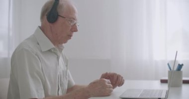 Yaşlanan profesör öğrencilere ders veriyor, internet üzerinden iletişim kuruyor, web sayfası ve video araması ile, evde oturuyor.