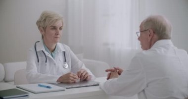 İki doktor klinikte konuşuyor, birbirlerine danışıyorlar, danışmanlık yapıyorlar, tıp uzmanları ve doktorlardan oluşan bir grup.
