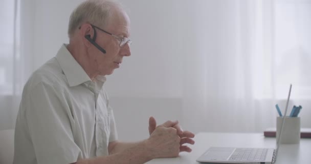 Hombre anciano se está comunicando con amigos o colegas por videollamada, hablando mirando la pantalla de la computadora portátil, comunicación en línea — Vídeos de Stock