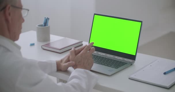 Male doctor is looking at green screen of notebook, communicating online, video call concept — Stock Video