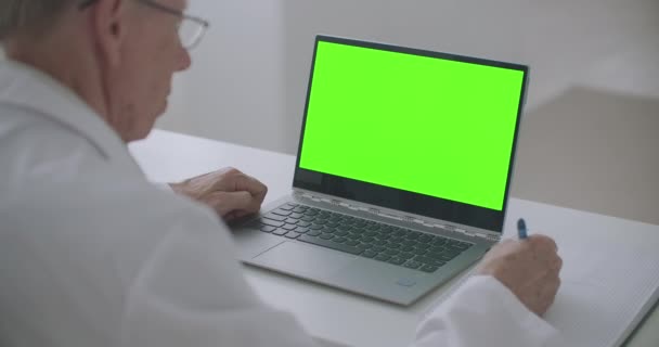 Notebook con schermo verde sul tavolo del terapeuta di lavoro in clinica, concetto di appuntamento medico online — Video Stock