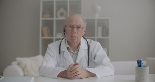 Retrato del profesor de medicina, la realización de webinar desde su oficina en la clínica, el hombre anciano está mirando a la cámara y hablando — Vídeos de Stock