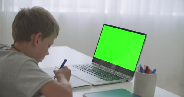 Niño está aprendiendo de forma remota, ver vídeo en el ordenador portátil y dibujar en papel a lápiz, pantalla de croma clave — Vídeos de Stock