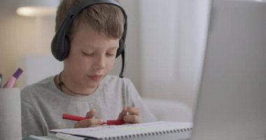Kafasında kulaklık olan küçük bir çocuğun portresi, odasında oturan bir çocuğun resmi.