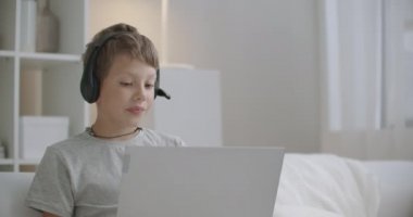 Evinin oturma odasında dizüstü bilgisayarı olan küçük bir çocuk internetten görüntülü konuşma, aktif ve pozitif çocuk portresi