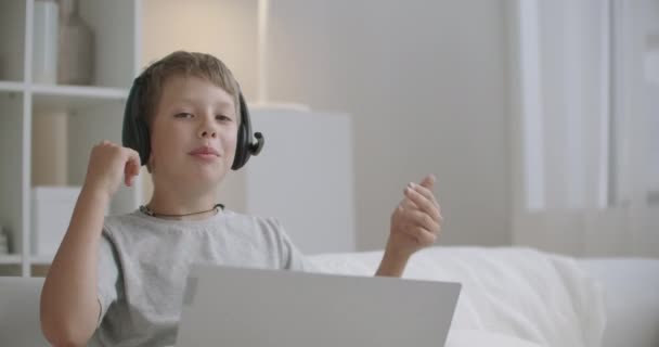 Niño travieso está charlando en línea por computadora portátil, niño activo y positivo, sentado en casa los fines de semana, retrato — Vídeos de Stock