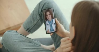 Kadın tıp asistanı beyaz önlük giyiyor, kulaklık takıyor akıllı telefondan uzak bir hastayı arıyor. Doktor sanal sohbet telefon uygulaması kullanarak müşteriyle konuşuyor. Teletıp, uzaktan sağlık hizmetleri 