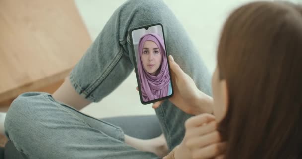 Feminino usando aplicativo médico em consultoria smartphone com mulher muçulmana árabe no médico hijab via videoconferência. Feminino usando bate-papo online para conversar com terapeuta familiar e pandemia de coronavírus. — Vídeo de Stock