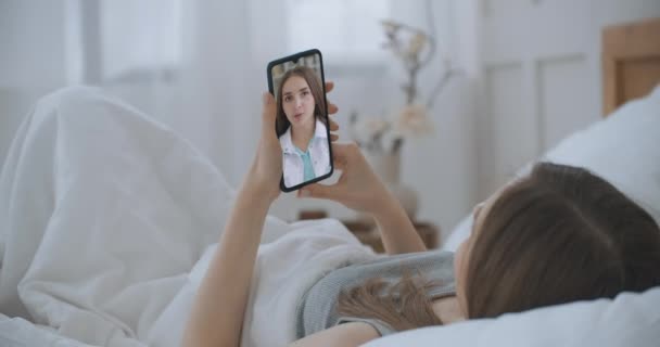 Young Girl Sick at Home Uso de Smartphone para hablar con su médico a través de la aplicación médica de videoconferencia. Hermosa mujer comprueba posibles síntomas con médico profesional, el uso de chat de vídeo en línea. — Vídeos de Stock