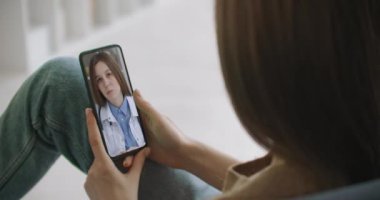 Kadın, video konferans aracılığıyla doktorla konuşmak için akıllı telefon uygulaması kullanıyor. Aile terapistiyle konuşmak için internet üzerinden sohbet eden ve koronavirüs salgını sırasında olası belirtileri kontrol eden bir kadın..