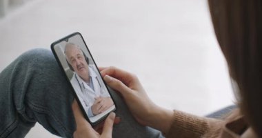 Kadın, video konferans aracılığıyla doktorla konuşmak için akıllı telefon uygulaması kullanıyor. Aile terapistiyle konuşmak için internet üzerinden sohbet eden ve koronavirüs salgını sırasında olası belirtileri kontrol eden bir kadın..