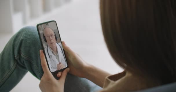 Žena pomocí lékařské aplikace na smartphone poradenství s lékařem prostřednictvím videokonference. Žena pomocí online chatu mluvit s rodinným terapeutem a kontroluje možné příznaky během pandemie koronaviru. — Stock video