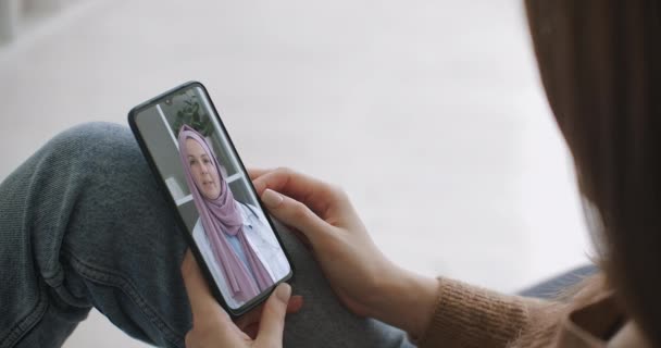 Kvinne som bruker en medisinsk app på smarttelefon for å rådføre seg med legen via videokonferanse. Kvinne som bruker nettprat for å snakke med familieterapeut og sjekker mulige symptomer under pandemi av coronavirus. – stockvideo