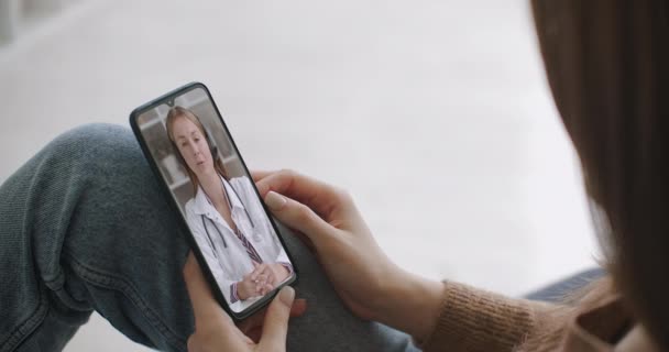 Donna che utilizza app medica su smartphone consultandosi con il medico tramite videoconferenza. Femmina che utilizza chat online per parlare con il terapeuta della famiglia e controlla i possibili sintomi durante la pandemia di coronavirus. — Video Stock