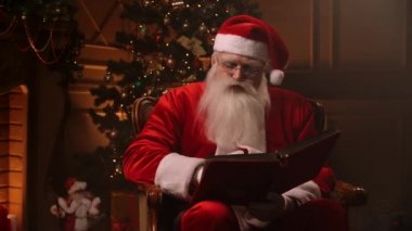 Noel Baba kostümü giymiş sakallı son sınıf öğrencisi temalı odada kırmızı kapaklı sayfaları karıştırıyor. Noel ruhu kavramı kapanıyor..