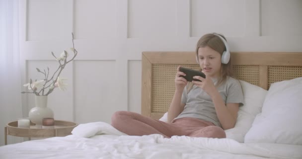 Kinderen en internet games, klein meisje speelt door smartphone zitten in de slaapkamer, internetverslaving, tijdverdrijf thuis tijdens zelf-isolatie — Stockvideo